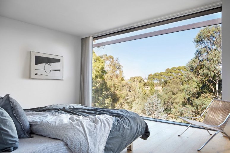 The master bedroom features a glass wall with views and minimal furniture