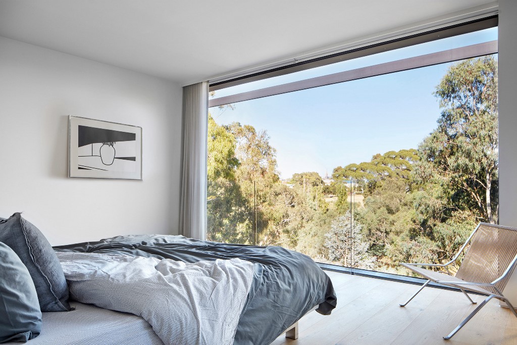 The master bedroom features a glass wall with views and minimal furniture