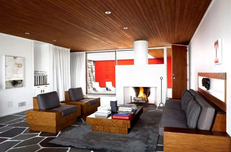 The living room shows off a large white hearth, grey furniture with stained wood parts