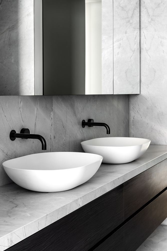 The bathroom is done with white marble, a large sleek wooden vanity and a mirrored cabinet