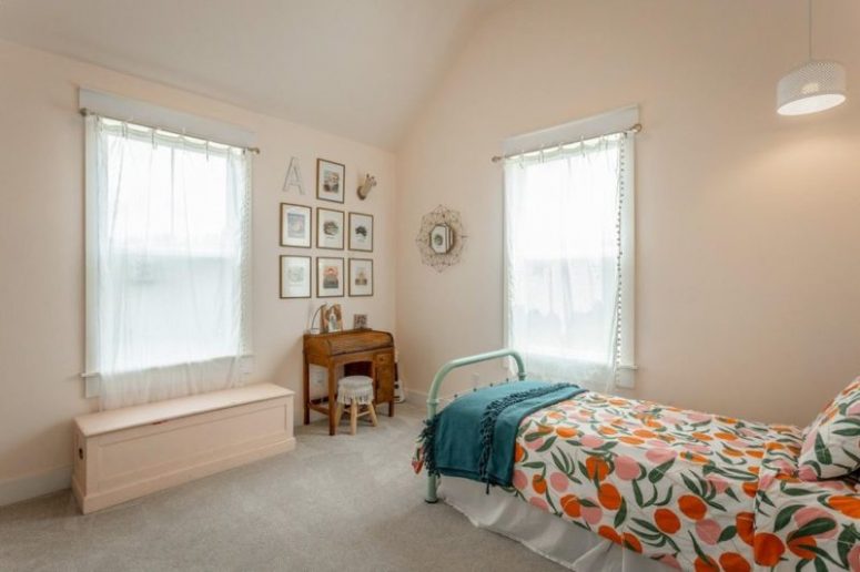 This bedroom done in blush shows off vintage furniture, a gallery wall and bright bedding