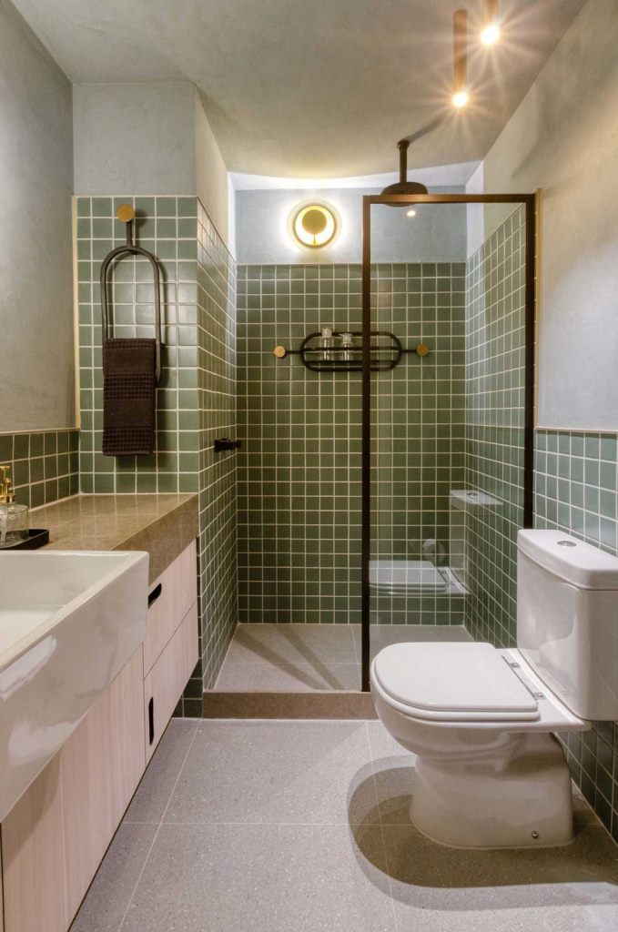 The bathroom continues mid-century modern theme in decor with its matte green tiles and neutral surfaces