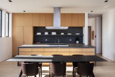 09 The kitchen is minimalist, with sleek neutral cabinets, a dark backsplash and there’s a laconic dining space with a marble table