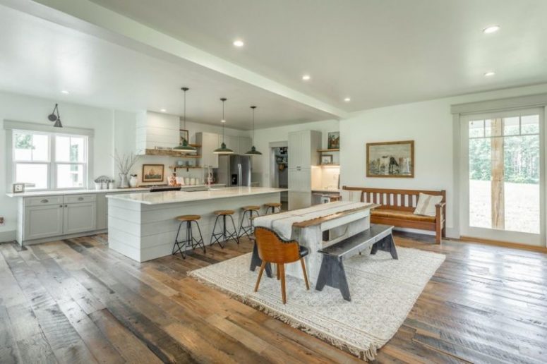 The kitchen is all-white and chalk painted, there's a small dining space with vintage furniture next to it