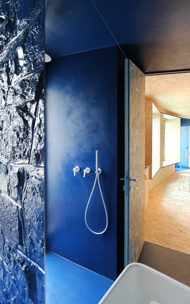 The shower space is also very bold blue, with a window, there's a bathtub