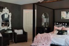 a chic and refined bedroom with black walls, a black bed and other sitting furniture, a catchy crystal chandelier and pink bedding