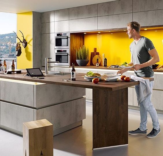 a chic contemporary kitchen with matte grey cabinets, a sunny yellow backsplash and a kitchen island with a wooden tabletop