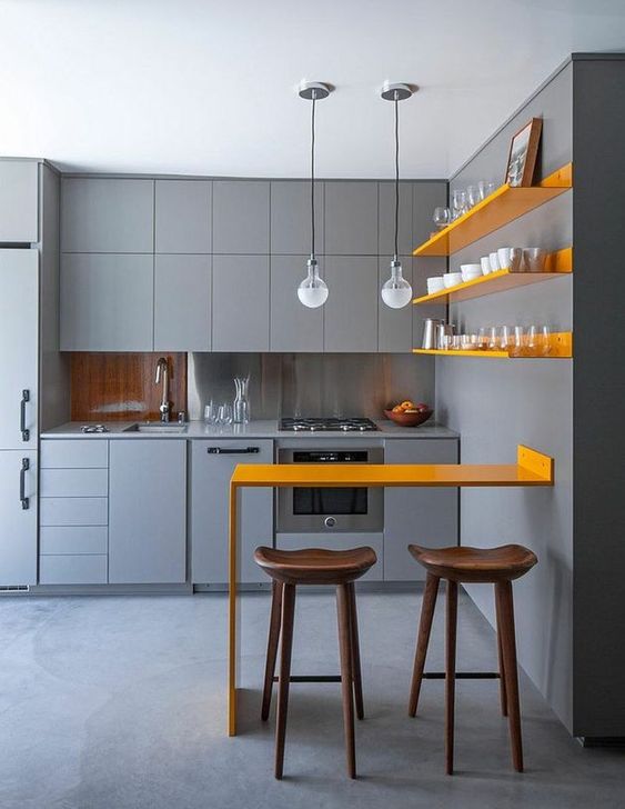 a chic minimalist kitchen with matte grey cabinetry, sunny yellow shelves and a matching counter for meals and drinks