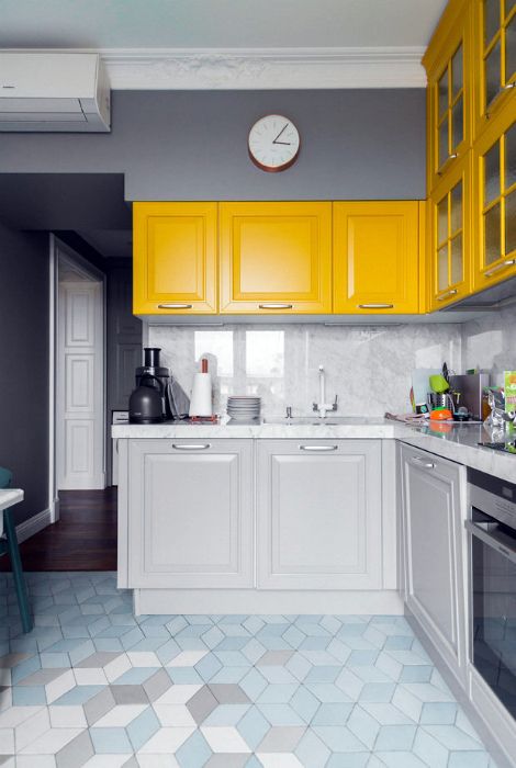 a chic modern kitchen with dove grey and sunny yellow cabinets, a white marble backsplash and countertops plus a tile floor