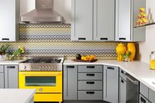 a cozy kitchen with dove grey cabinets, a bright yellow cooker and accessories plus a mosaic tile backsplash