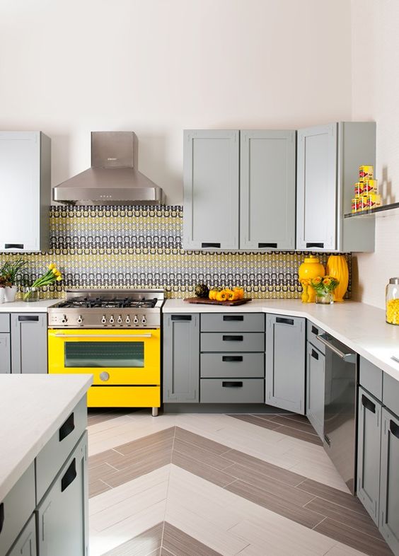 a cozy kitchen with dove grey cabinets, a bright yellow cooker and accessories plus a mosaic tile backsplash