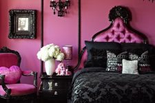 a dramatic black and pink bedroom with bright pink walls, a chair, a pink bed, a black chandelier, bedding and frames
