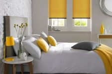 a minimalist grey and yellow bedroom with simple and minimal furniture, a grey bed, yellow linens and neutral textiles