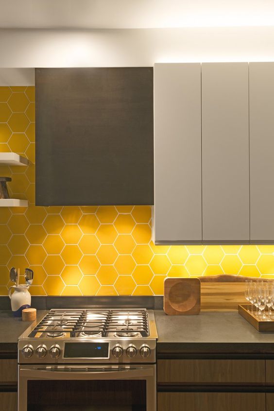 a minimalist kitchen with grey dove grey and wooden cabinets, a yellow hex tile backsplash and concrete countertops