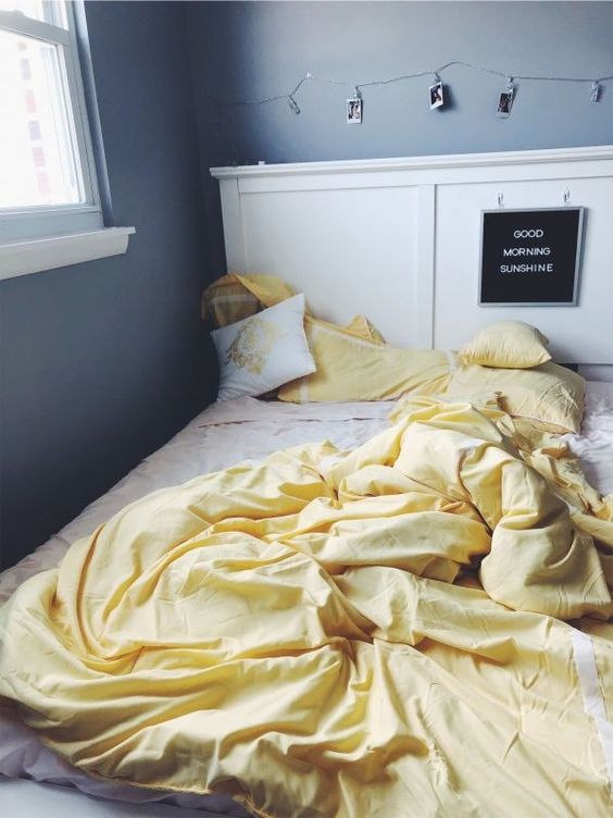 a modern graphite grey bedroom with a white bed, lights and photos and lemon yellow bedding to spruce up the space