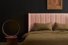 a moody and refined bedroom with black walls, a blush bed, a vintage artwork, green bedding, a bold table lamp