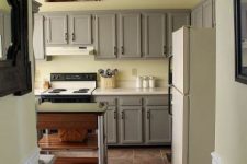a peaceful kitchen with pale yellow walls, traditional grey cabinets with paneling and a metal and wood kitchen