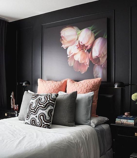 a refined moody bedroom with black walls, black furniture, pink and grey bedding and a pink floral artwork