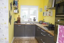 a simple modern kitchen with yellow walls, glossy grey cabinets and wooden countertops for a contrasting look
