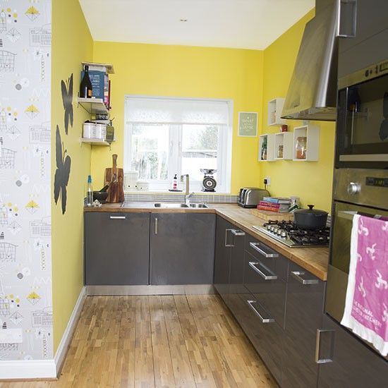 a simple modern kitchen with yellow walls, glossy grey cabinets and wooden countertops for a contrasting look