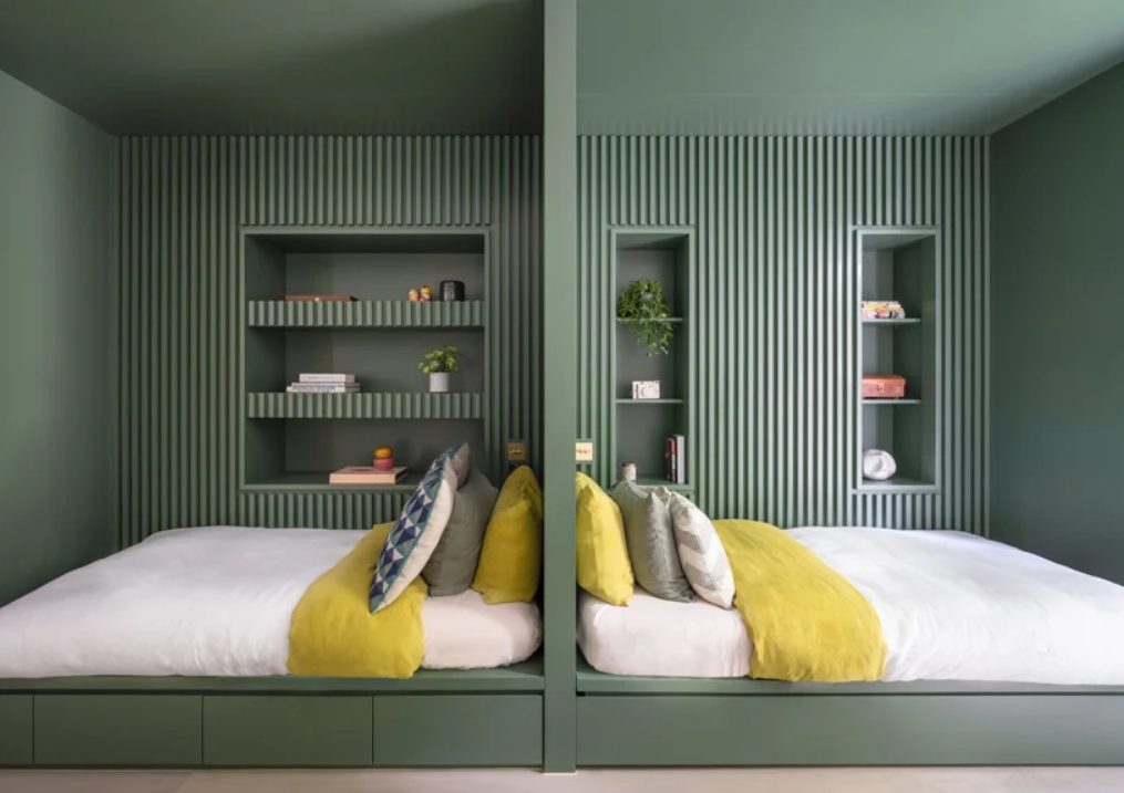 Here's a peaceful double bedroom done in greens, with wooden slabs and niches for storage
