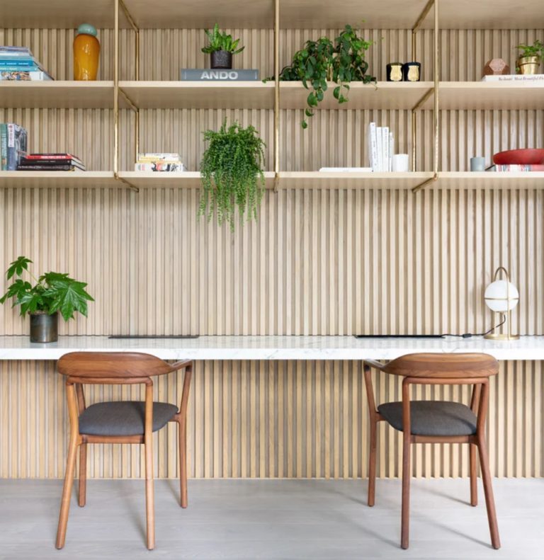 The home office is shared, with a floating desk, lots of shelves hanging and chic chairs