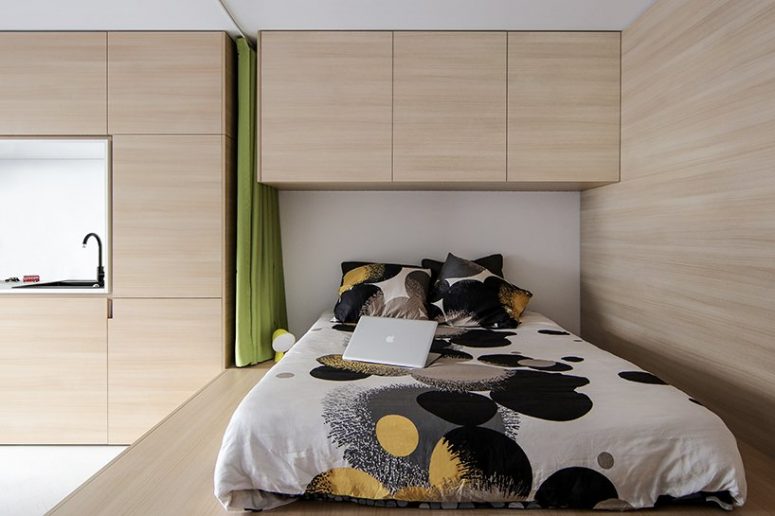 The kitchen and sleeping zone are next to each other and are done with the furniture of the same look