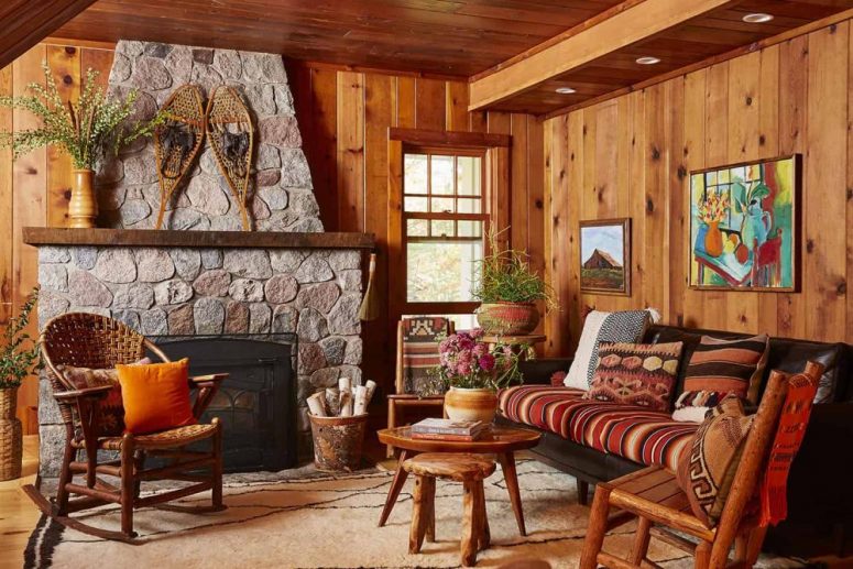 The living room is done with stained wood, vintage rustic furniture and a large stone hearth
