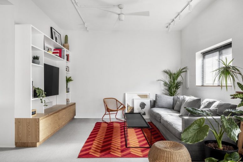 The living room is very comfy, with a bright rug for an accent, potted plants and oak