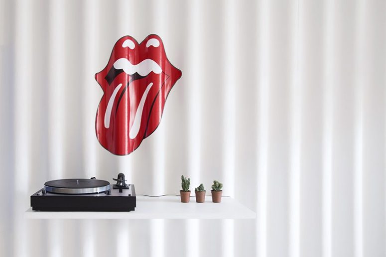 A white shelf with a turntable and a lips & tongue rolling stone sticker identifies a music corner