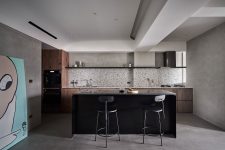 05 The kitchen is done with stained wooden cabinets, a black kitchen island and a cool terrazzo backsplash