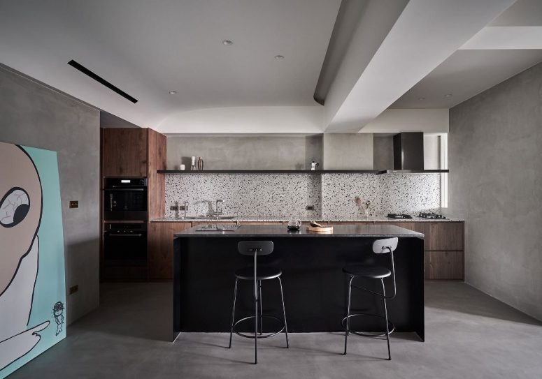 The kitchen is done with stained wooden cabinets, a black kitchen island and a cool terrazzo backsplash