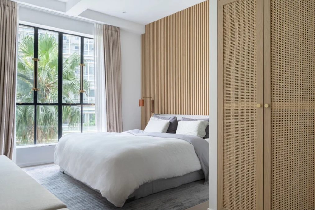 The master bedroom is done with a glazed wall, a wooden slab wall and delicate linens