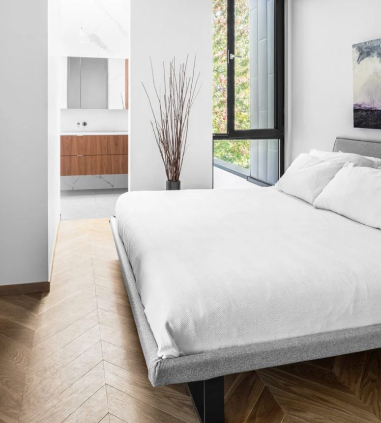 The bedroom here is small yet comfy, with a large bed, a tall window and some art