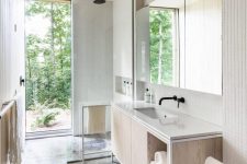07 The bathroom is all-neutral, with white tiles and neutral plywood and a gorgeous forest view