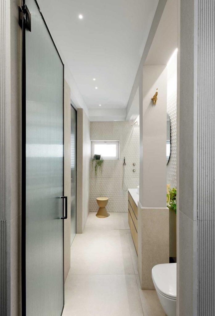 The bathroom is done with concrete andd white tiles, there's a shower and a large vanity for storage