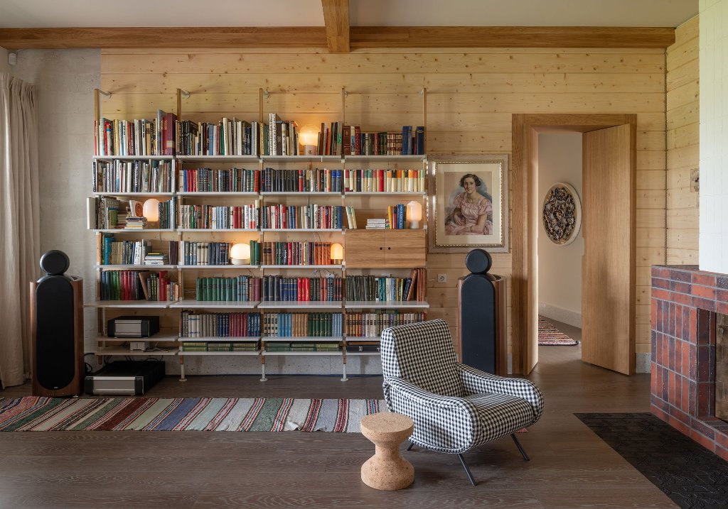 There's a large open shelf, a plaid chair and a fireplace for a cozy reading nook