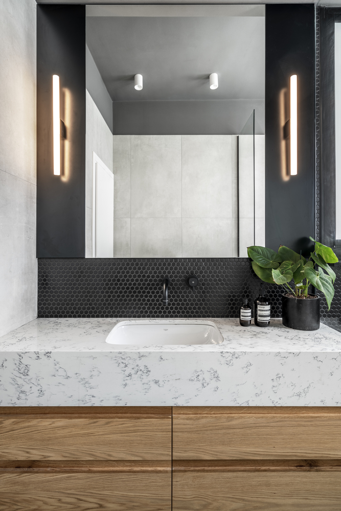 The white marble complements the wood and the dark wall and floor tiles, establishing harmony in here