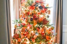 15 a gorgeous bright Thanksgiving tree with lights, ornage, gold and black ornaments, faux leaves, foliage and a pumpkin on top