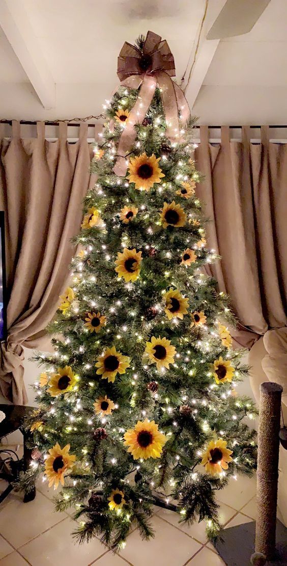 a simple and bright fall tree with lights, pinecones, faux sunflowers and an oversized brown bow on top