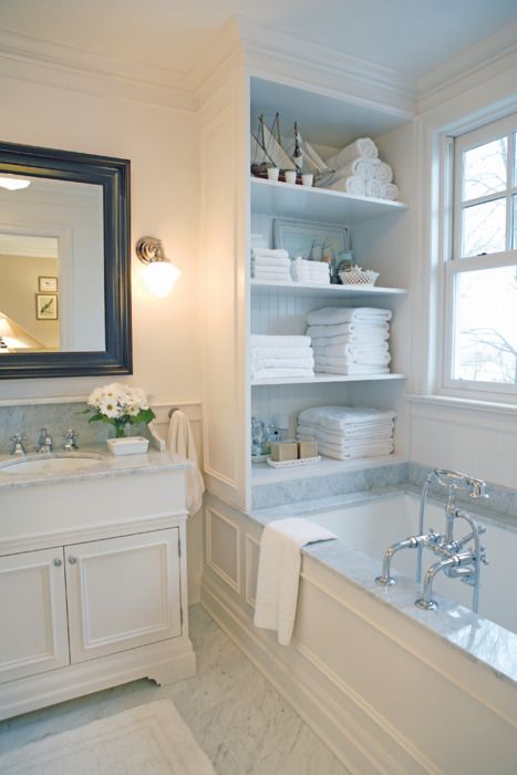 a cabinet with open shelves placed over the tub is a stylish storage unit you may rock