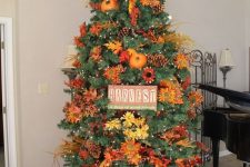 23 a gorgeous and bright Thanksgiving tree with lights, pinecones, bright faux blooms and leaves, branches, a sign and pumpkins