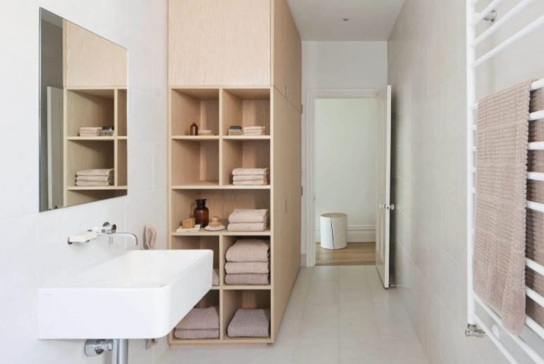a neutral minimalist bathroom showing off a large cabinet for storage that ends up with open shelving for more comfort