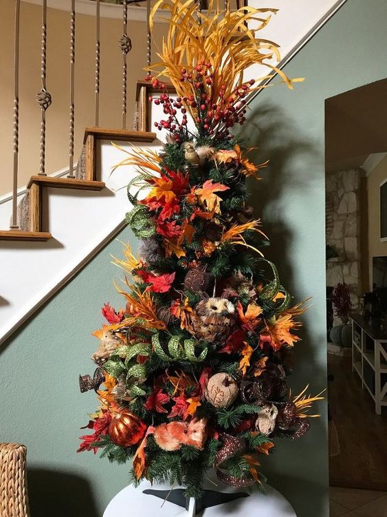 a vintage rustic tree with faux pumpkins, leaves, branches, berries on top and a faux owl is bold