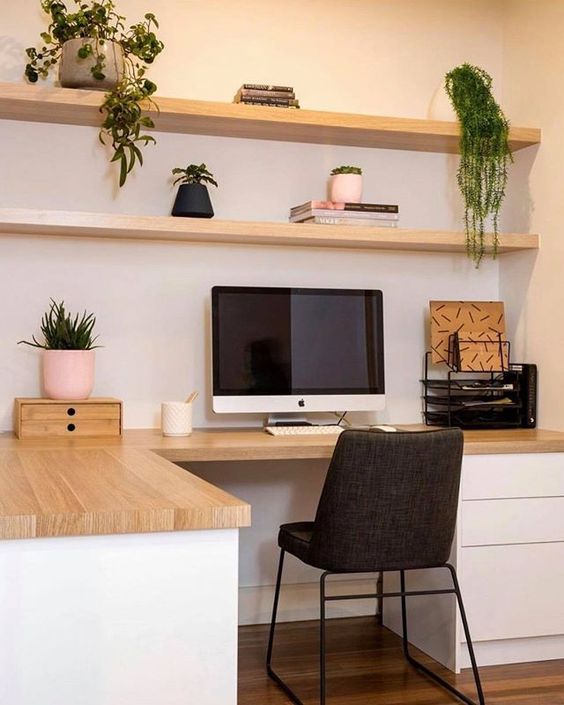 a Scandinavian home office with open shelves, a corner desk with storage, a black chair and potted plants
