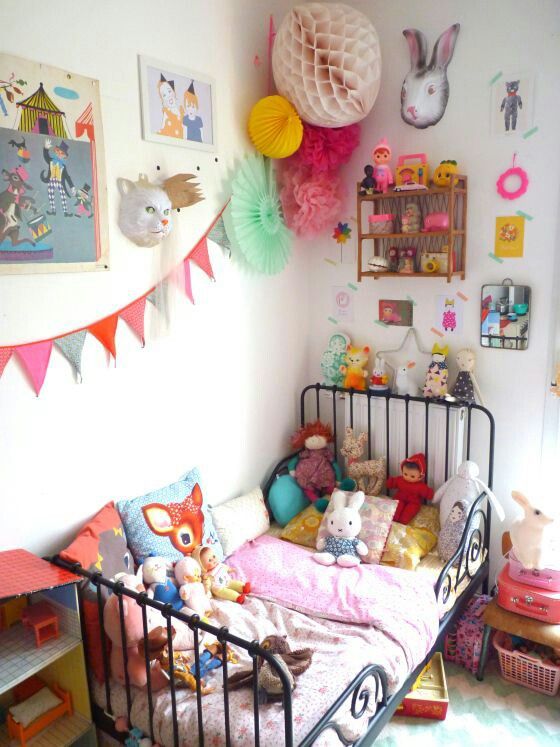 a bold kid's room with colorful art, accessories and toys, colorful bedding, pompoms and garlands