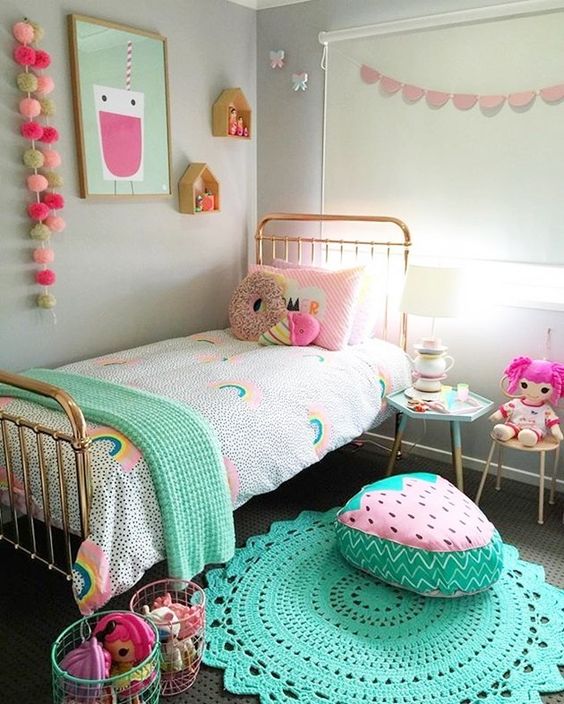 a bright and pastel kid's room with colorful garlands, bedding, toys, rugs and cool foodie pillows