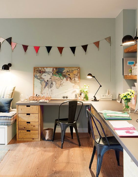 a bright home office with an L-shaped desk, black metal chairs, a bunting, open shelves and decor