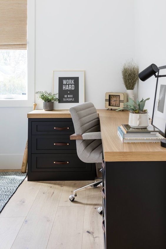 a chic modern working space with a black corner desk, a grey chair, some potted plants and a black table lamp