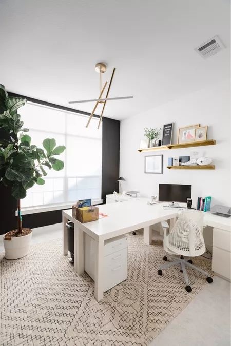 a modern home office with a black accent wall, a white corner desk, a couple of chairs, some storage units, open shelves